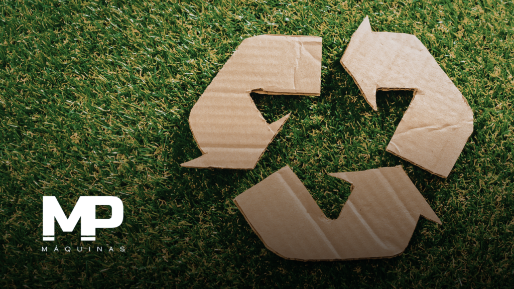 Grama com um símbolo de reciclagem feito de papelão em cima da grama para representar o artigo: Embalagem de Papelão Ondulado e Circularidade